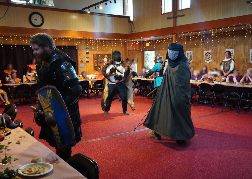 John Latson gives kids a close-up look at his gear while Josh Campbell and Conner Hummel show off their outfits. April 16, 2026. Kids' faces are blurred for identity protection.